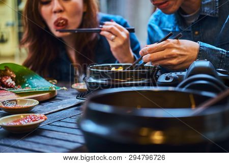 Young Chainese Couple Trying Asian Food At First Time. Couple Is Siting At Cafe Outside. They Have C
