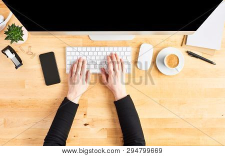 Female Hands Working On Modern Desktop Computer. Top View Of Wooden Office Desk With Large Desktop C