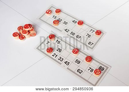 Bingo Or Lotto Game. Wooden Kegs Of Lotto On Cards. Cards And Chips For Playing Bingo On A White Tab