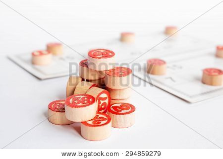 Bingo Or Lotto Game. Wooden Kegs Of Lotto On Cards. Cards And Chips For Playing Bingo On A White Tab