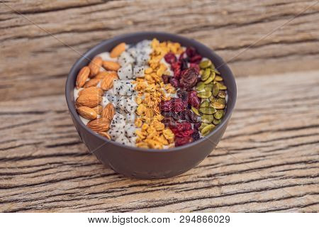 Mango Smoothies Bowl With Almond, Dragon Fruit, Dried Cherries, Pumpkin Seeds And Granola On Wooden 