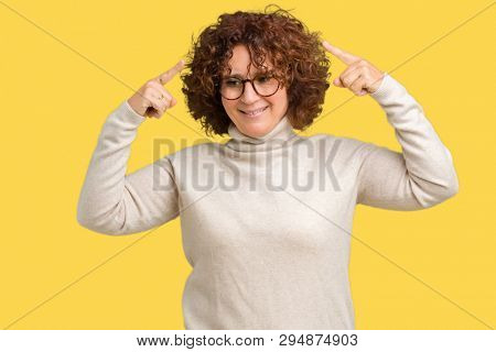 Beautiful middle ager senior woman wearing turtleneck sweater and glasses over isolated background Smiling pointing to head with both hands finger, great idea or thought, good memory