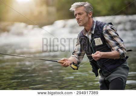 Mature man fly fishing in beautiful river