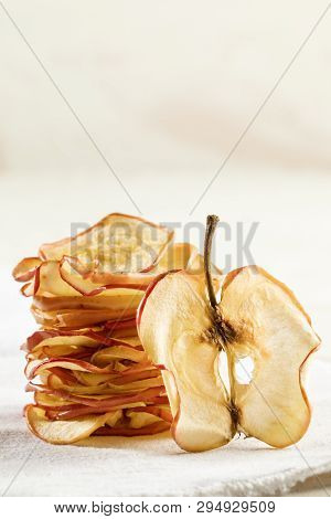 Vertical Pile Of Apple Chips With One Slice Standing Near It On White Background.