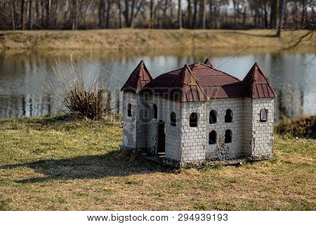Doghouse In Shape Of A Castle On The River Bank In A Park