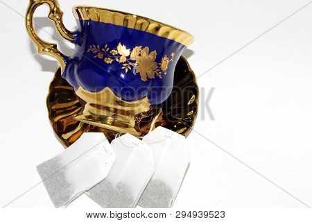 Tea Set: Cup And Saucer With Three Bags Of Disposable Tea On White Background