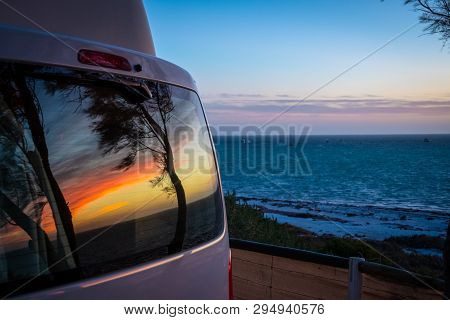 Reflection Of Tree Silhouettes On Campervan Window In Front Of Indian Ocean In Australia