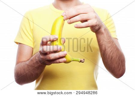Guy Holding And Opening Yellow Banana Over White Background. Studio Shot.