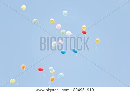 Red, White, Yellow Blue And Green Balloons Fly Across The Blue Sky.