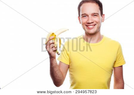 Smiling Handsome Guy Holding Yellow Banana Over White Background. Studio Shot.
