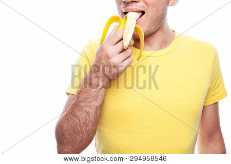 Smiling Handsome Guy Holding And Biting (eating) Yellow Banana Over White Background. Studio Shot.