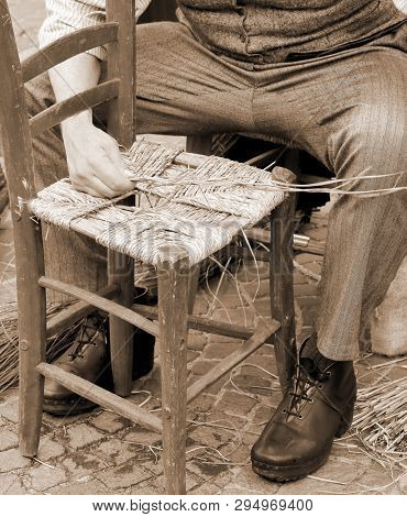 Senior Man Repairs An Old Chair With Vintage Old Toned Effect
