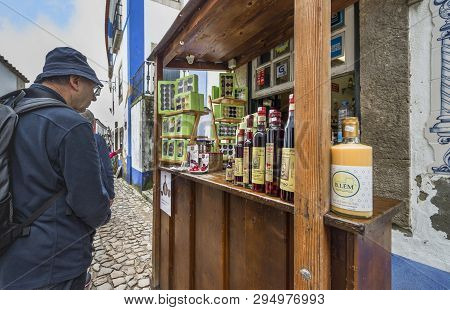Obidos, Portugal - April 2018: Tourists At The Street Ginja Store In The Old Town