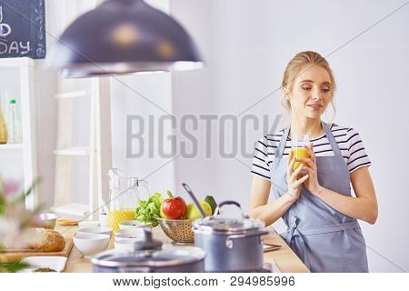 The Girl At The Table In The Kitchen With A Glass Of Orange Jui