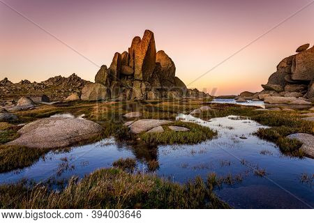 Rocky Tor In Snowy Mountains Surrounded By Blue Pools With Dusk Light