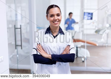 Portrait Of Cheerful Dentist In Dental Reception With Arms Crossed Looking At Camera Wearing Uniform