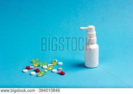 Medicines - Tablets, Pills And Capsules With A White Can Of Throat Spray On A Blue Background.