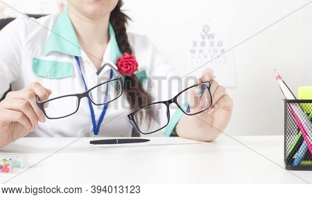 Doctor Ophthalmologist Holds In His Hands Two Glasses For The Eyes. The Concept Of Choosing The Righ