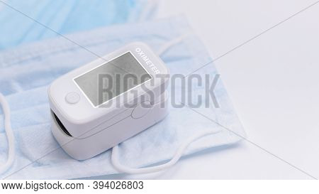 Portable Pulse Oximeter On Background Face Mask To Monitor Oxygen Level At Home. Covid-19, Healthcar
