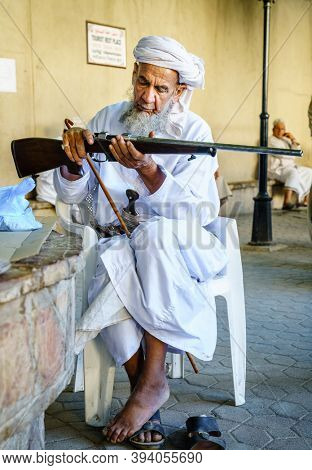 Nizwa, Oman, December 2, 2016: An elderly man is inspecting a hunting rifle at the Friday gun market in Nizwa, Omam