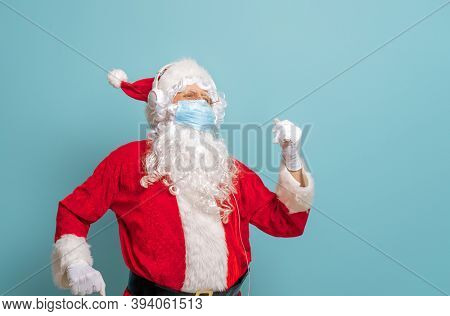 Merry Christmas and Happy Holidays! Santa Claus in face mask on bright color background. Covid-2019