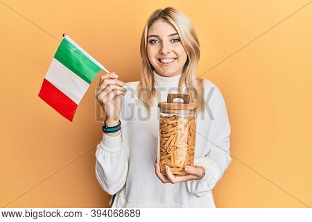 Young caucasian woman holding jar of macaroni pasta and italian flag smiling with a happy and cool smile on face. showing teeth. 