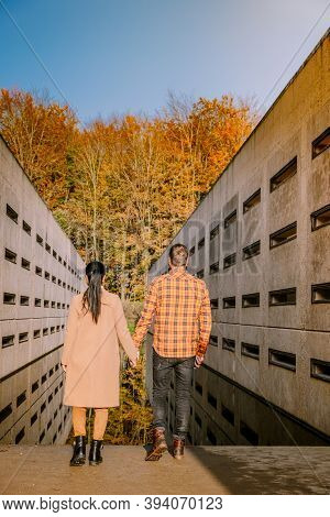 Couple Men And Woman Hiking In The Forest During Autumn And Small Streaming Water River With Fall Co