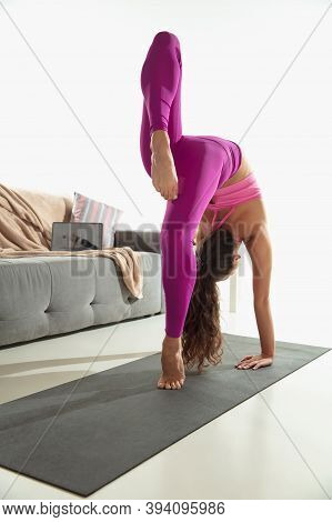 Vitality. Beautiful Young Woman Working Out Indoors, Doing Yoga Exercise On Gray Mat At Home. Long H