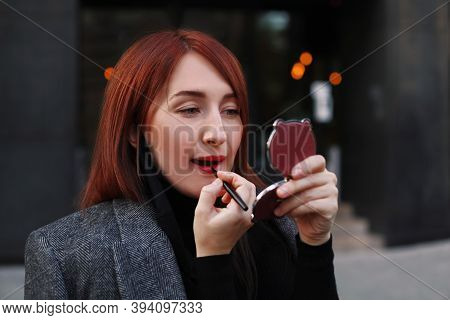 Redhead Caucasian Business Woman Looking At Little Pocket Mirror And Applying Red Lipstick After Wor