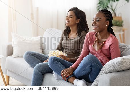 Two Black Girlfriends Having Fun At Home, Watching Comedy And Eating Popcorn, Copy Space. Laughing A