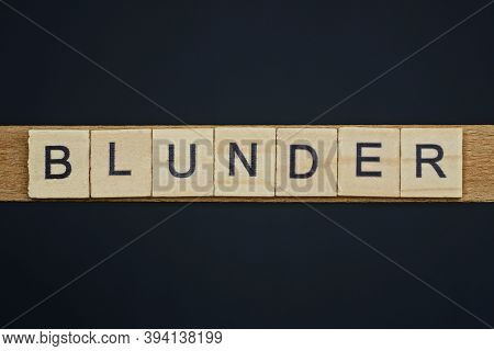 Gray Word Blunder From Small Wooden Letters On A Black Table