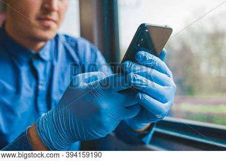 A Guy In Protective Medical Gloves Holds A Phone And Spends Time In It, Close-up