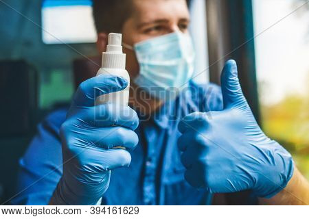 A Man On The Background In A Protective Mask Holds An Antiseptic In His Hand In Medical Gloves And S