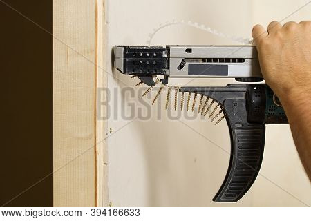 Room Repair. Building. Worker Fastens Drywall With A Screwdriver Close Up. Fixing Drywall To Wood Fr