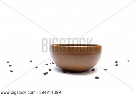 Flying Coffee Beans Into A Brown Bowl On A White Background, Close-up. Blurred