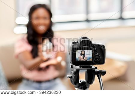 blogging, videoblog and people concept - happy smiling african american female beauty blogger with camera and perfume videoblogging at home