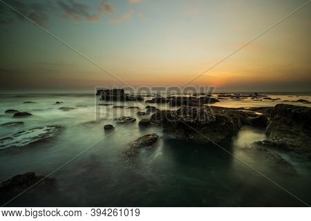 Amazing Seascape For Background. Beach With Rocks And Stones. Low Tide. Motion Water. Clear Sky. Sun
