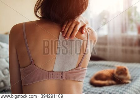 Close Up Of Patch For Back Pain Relief. Woman Appied Plaster On Shoulder Blade At Home Suffering Fro