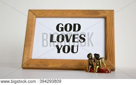 Wooden Picture Frame With Inscription From Bible On Beautiful White Fon. Two Bronze Angeles On The T