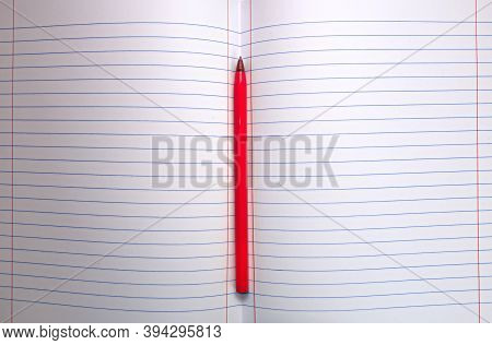 Red Pen Lying In A Notebook In A Ruler Between Two Pages.
