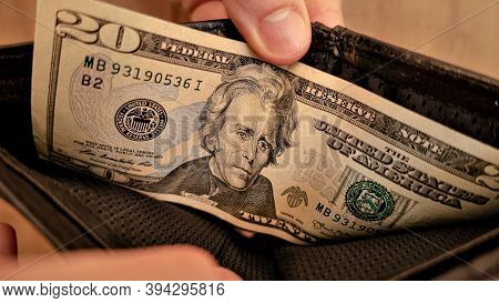 A Twenty Dollar Bill In A Black Wallet. Human Hands Open The Wallet.