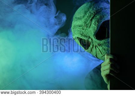 Alien Is Hiding In The Smoke On Dark Background.