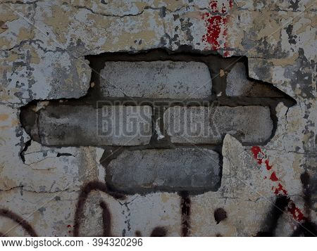 old white and gray brick wall with cracked lettering close up