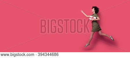 Curly Haired Woman Is Running After Somebody Holding A Present And Gesturing With Hands The Wait Sig