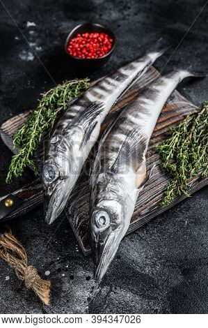 Raw Icefish On A Wooden Cutting Board. Black Background. Top View