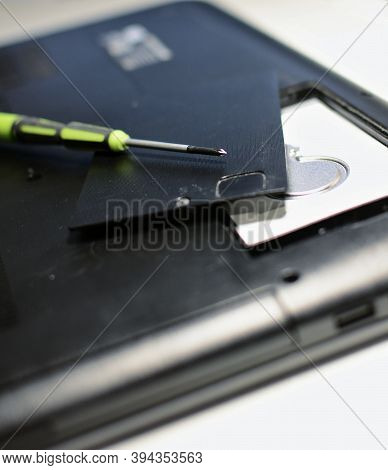 Closeup Of Screwdriver And Hard Disk During Repairing Of Old Laptop.