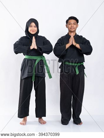 Veiled Women And Men In Pencak Silat Uniforms With Green Belts Perform Respectful Hand Gestures