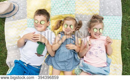 Funny Kids Fooling Around At Summer Camp On Vacation. Children Try On A Cucumber Mask. Unschooling C