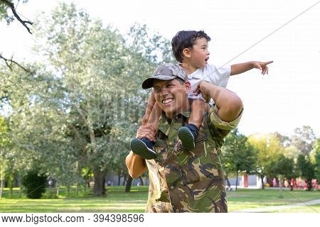 Exited Little Boy Sitting On Dad Neck And Pointing Away. Caucasian Father Holding Son Legs, Smiling,