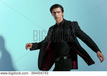 Young Man Poses In Studio With Attitudine, Looking At Camera, Dresser In Suit, Isolated On Blue Back